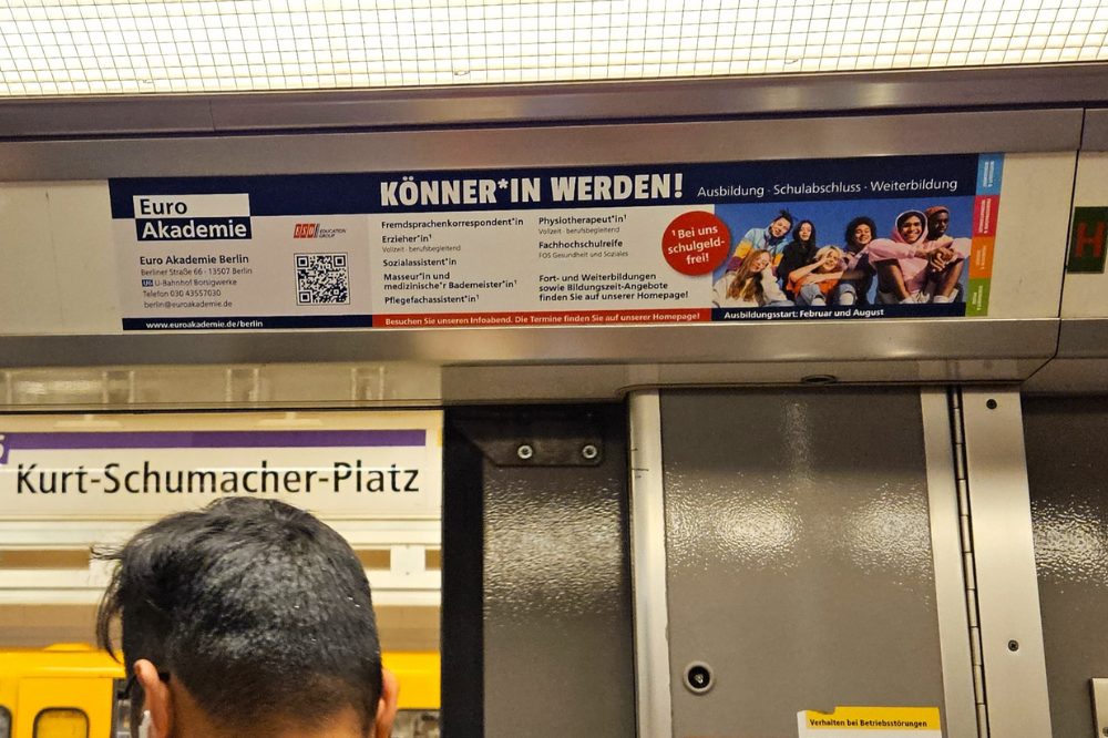 Aus einer U-Bahn steigen gerade mehrere Menschen aus dem Zug auf den Bahnhof U Kurt-Schumacher-Platz aus. Über dem Ausgang der U-Bahn hängt eine U-Bahn Innenwerbung des Weiterbildungsinstituts Euroakademie. Mit der Werbung wird für neue Studierende geworben.