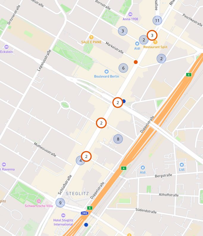 Auf diesem Kartenausschnitt sieht man die Schloßstraße in Berlin Steglitz. In der Mitte sieht man den Standort von unserem Kunden Dydo als blauen Punkt markiert. Einige orange Kreise mit Zahlen eigen die ausgewählten Screens für die programmatisch digitale Außenwerbekampagne. Andere Kreise sind nicht hervorgehoben. This map shows the Schloßstraße in Berlin Steglitz. In the center you can see the location of our customer Dydo marked as a blue dot. Some orange circles with numbers indicate the screens selected for the programmatic digital outdoor advertising campaign. Other circles are not highlighted.